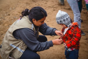 woman helping a child zip up a jacket