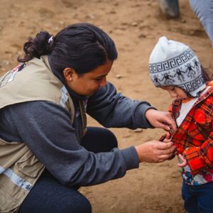 woman helping a child zip up a jacket