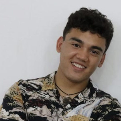 Joseph Babauta smiling in front of white wall.