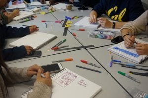 fellows around a table with colorful pens and notebooks for sketching